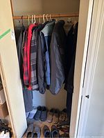 Full closet view showing jackets hung on rod and shoes on floor below.