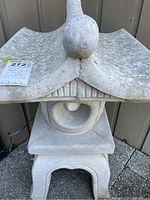 Front view of the Asian style patio light showing the pagoda-like roof, circular center opening, and the light bulb inside.