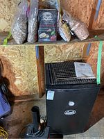 Full setup showing wood chip bags on shelf above portable smoker and smoke generator in foreground