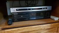 Photo of Yamaha DVD-S657 player stacked above Pioneer PD-4500 CD player on wooden shelf showing front panels and remote controls.