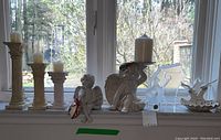 Wide view of shelf showing candle holders with candles, cherub figurine, Goebel horse, and golfer figurine on shells