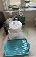 Photo showing Philips electric slicer, various blades, salad spinner, green storage containers, glass jar, and wooden pepper mill on a counter.