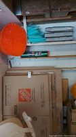 Photo of large orange bubble wrap roll, blue foam wrap sheets, green stretch wrap roll, and stacked large moving boxes from Home Depot.