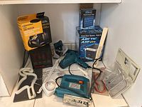 Full view of all items together in a shelf: jig saw, timer, Arctic Air Ultra, hair dryer, cord protector, heat machine heater