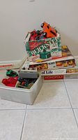 Cardboard box of toy vehicles stacked on top of three board game boxes