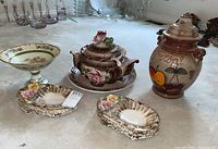 Photo of Rumtopf pot, floral tureen, platter, and two floral serving dishes arranged on a table.