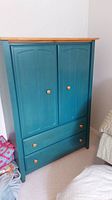 Front view of teal wardrobe with natural wood top, two doors, two drawers