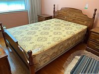 Full view of wooden bed frame with matching nightstands and mattress placed on frame, visible turned posts and medium brown finish.