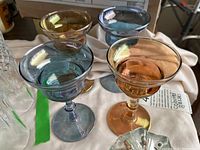 Four colored glasses arranged on a table, visible colors amber, blue, and smoky gray, showing size and shape.