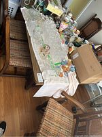 Photo showing arrangement of five wooden dining chairs around a table with various glassware and other items on the table.