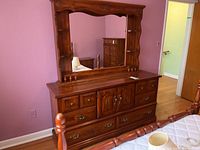 Front view of wood dresser with large mirror showing drawer and cabinet layout and overall condition.