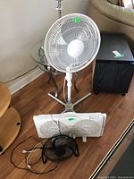 Three fans displayed: white pedestal fan, white twin window fan, and small black desk fan.