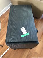 Top view showing black wood grain textured surface with a white lot number tag.