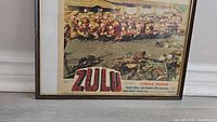 Framed lobby card showing a battle scene from the movie 'Zulu'. The movie title and credits are visible.
