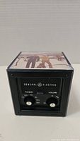 Front view showing General Electric brand, tuning dial, volume knob, and frequency display.