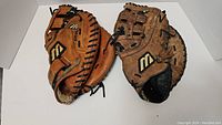 Both Mizuno baseball gloves placed side by side, showing different levels of wear and Mizuno logos.