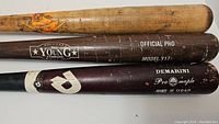 Three baseball bats laid side by side showing brand names and conditions.