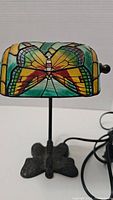Photo of the lamp showing the colorful stained glass butterfly design on the shade