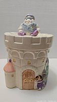 Front view of the ceramic castle cookie jar with Humpty Dumpty figure on the lid and castle door design.