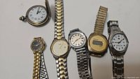 Six watches in a mixed lot including a pocket watch, gold-tone and silver-tone wrist watches, and a digital watch.