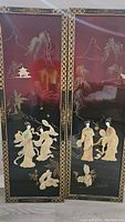 Pair of vertically oriented black lacquered wall panels with gold borders and mother of pearl inlay featuring Asian styled figures, landscape, and architectural elements.