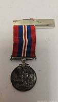Full view of World War II Canadian Defense Medal showing ribbon, suspension bar, and medal.