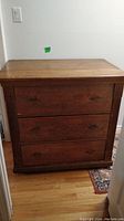 Front view of antique solid wood dresser with three drawers showing overall condition and design.