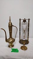 Group photo of the brass ewer pitcher, candle holder, and hourglass showing overall size and condition.