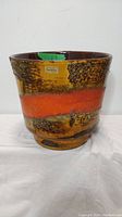 Front view showing the textured burnt orange and yellowish-brown banded ceramic planter with original Carstens West Germany sticker.