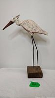 Front and side view of vintage handmade wooden stork carving with textured white paint and brown beak.