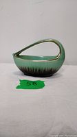 Side view of green and brown ceramic candy dish with gold-trimmed handle, showing glossy finish and shape