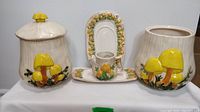 Group photo of vintage mushroom-themed ceramic set with two canisters, one creamer, and two platters.
