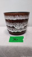 Front view of vintage ceramic planter showing brown base with white foamy horizontal bands