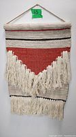 Front view of wool wall tapestry showing red triangular pattern with black stripes and fringe