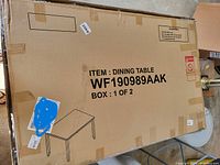 Photo of large cardboard box labeled as a dining table, indicating item still packaged and unassembled.