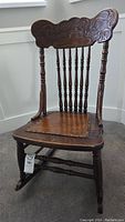 Front view of antique solid wood rocking chair with carved top rail and replaced caning seat.