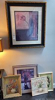 Image showing large framed art print of pink tulip on wall and four smaller framed artworks leaning below it