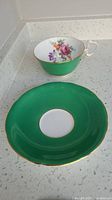 Photo showing the green porcelain saucer and teacup with floral interior and gold trim