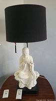 Full view of Buddha statue table lamp with black lampshade and pull chain