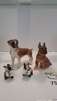 Four ceramic boxer dog pieces: two standing dog figurines and two ceramic dog head salt and pepper shakers labeled 'S' and 'P' on white bibs.
