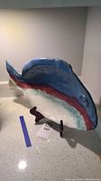 Side angle of ceramic fish dish on display stand. Shows the colors blue, red, and white.
