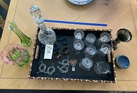 Full view of crystal decanter, sixteen crystal glasses, green and pink Fenton glass vases, and other small glass items in a tray.