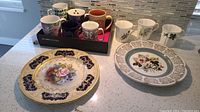 Overview of all eight coffee cups and two decorative plates on countertop