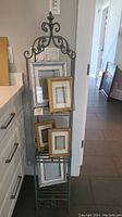 Metal decorative three tiered stand with five assorted photo frames displayed on it.