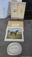 Overview photo showing the art prints with original packaging and accompanying cowboy hat on carpeted floor.