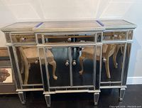 Full front view of silver leaf buffet cabinet showing mirrored panels and decorative knobs