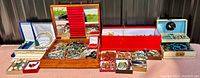 Overall display of wooden box, red and blue jewelry cases with assorted jewelry laid out