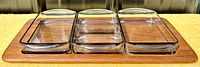 Top angled view showing teak tray with three nested smoked glass buffet dishes, rectangular and square shapes visible.