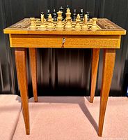 Front view of chess table showing board, tapered legs, drawer and stored pieces