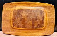 Top-down view showing the rectangular teak tray with a raised end-grain teak block center in decorative pattern and smooth surface.